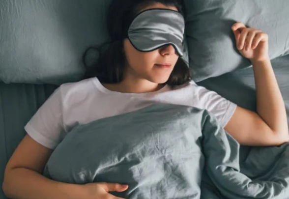 A person sleeping in bed with a blindfold

Description automatically generated