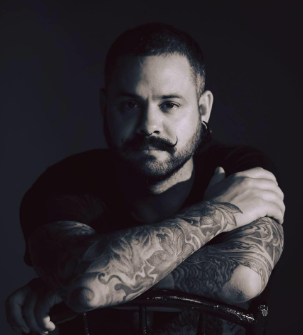 A person with tattoos on his arms
Description automatically generated
