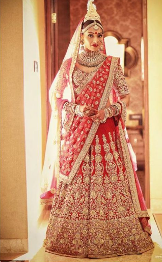 A person in a red and gold bridal dress
Description automatically generated