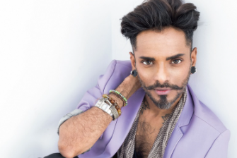 A person with a beard and mustache wearing a purple jacket
Description automatically generated
